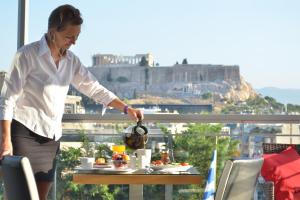 雅典雅典卫城阿米精品酒店的站在阳台上的女人,有桌子和食物