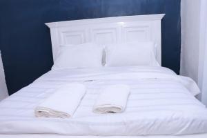 NyahururuLulu Stays 1 Bedroom的白色的床、白色枕头和毛巾