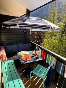 夏蒙尼-勃朗峰Le Petit Cham的阳台配有桌椅和遮阳伞