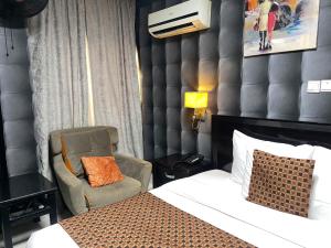 阿布贾Newland Luxury Hotels and Apartments的配有一张床和一把椅子的酒店客房