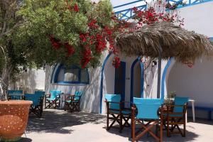 佩里萨Santorini Seaside Retreat - Flora's Summer Escape的草伞下的一组桌椅