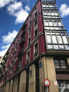 毕尔巴鄂Monappart Cristo Historic Apartment with Parking的一条高大的红色建筑,街上有窗户