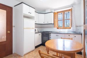 库利亚Casa del Practicant的厨房配有白色橱柜和木桌