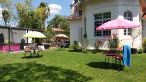 朗通Villa Glen-Tara的一个带桌椅和粉红色雨伞的院子