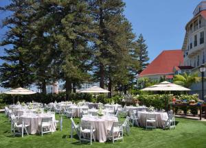 圣地亚哥德尔科罗纳多希尔顿Curio精选酒店的一组桌子,配有白色的椅子和遮阳伞