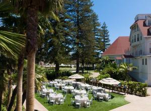 圣地亚哥德尔科罗纳多希尔顿Curio精选酒店的餐厅拥有白色的桌子和遮阳伞,并种植了棕榈树。