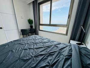 海法Luxurious Beach apartment的一间卧室设有一张床和一个大窗户