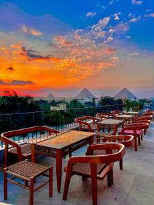 开罗Almas Pyramids Hotel的阳台上的一排桌子和长椅,享有日落美景