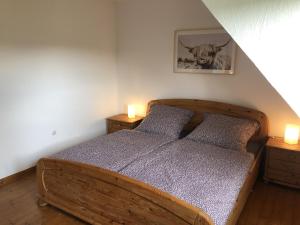 巴特贝勒堡Ferienhäuser am Wisentpfad的一间卧室配有一张木床,桌子上配有两盏灯