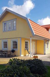 哥德堡Gula huset的黄色的房子,有橙色的屋顶和庭院