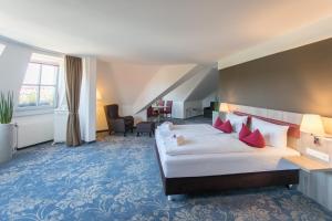 路德斯塔德·威特比martas Hotel Lutherstadt Wittenberg的酒店客房配有一张带红色枕头的大床