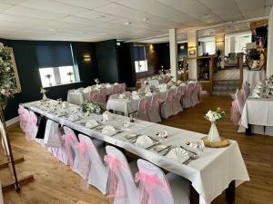 沃金顿威弗利酒店的宴会厅配有白色桌子和粉红色椅子