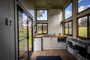 WindeyerSithuri Tiny House的厨房配有白色橱柜、窗户和柜台。