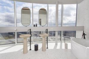 维尔纽斯Vilnius TV Tower Apartments DEBESYS的浴室配有2个盥洗盆、浴缸和镜子