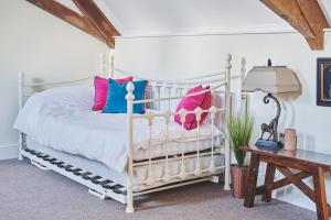 HolmesfieldHidden Hayloft的卧室配有白色床和粉红色及蓝色枕头