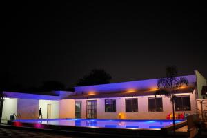 博帕尔THE ROYAL YARDS RESORT的一座晚上设有游泳池的房子