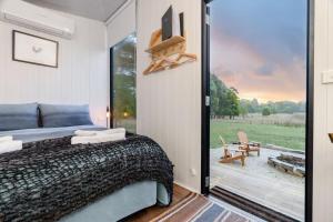 AshbourneLeft Field Tiny House的一间卧室设有一张床和一个滑动玻璃门
