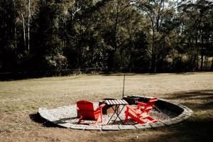 KurrajongHidden Creek Tiny Home的田野上的两张红色椅子和一张桌子
