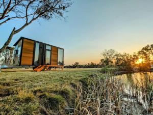 ToogoomTurtle Island Lakeside Tiny House 2的田野上的玻璃房子,带长凳