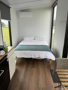 Otaki BeachRangiuru Stream Tiny home的一间卧室设有一张床和一个大窗户