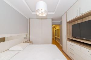 巴拉奈里奥-坎布里乌Amplo Apto 2sui+1Q Vista Mar 50m da Praia的卧室配有白色的床和平面电视。