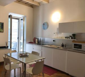 维杰瓦诺Emma Home adiacente alla Piazza Ducale的厨房配有白色橱柜和桌椅