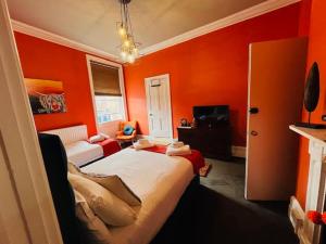 布由德利horn and trumpet的一间卧室拥有橙色的墙壁,配有一张床和一张沙发