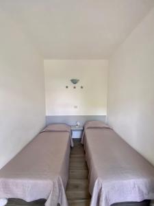 阿祖罗港Bed & Breakfast Alex的配有白色墙壁和木地板的客房内的两张床