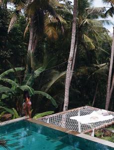 珀尼达岛SPICE TRADER的站在棕榈树游泳池旁的女人