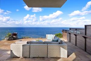 Curl CurlCurley Sunrise - Oceanfront的天井配有沙发,背景为大海