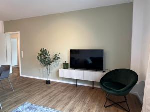 汉堡Business Apartment Kranich: 3 Zimmer, Top Infrastrukturlage HH Langenhorn, Nähe Airport的一间带电视和椅子的客厅