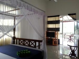 乌纳瓦图纳Coral Palm Villa and Apartment的一间卧室配有一张带天蓬的床和一台电视