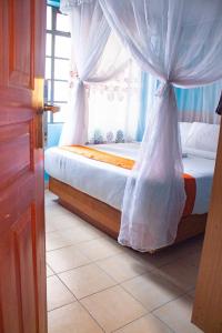 内罗毕Deka Self Contained Rooms的一间卧室配有一张带天蓬和窗户的床