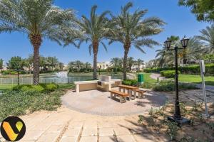 迪拜Vogue Villa Near Golf/Ski Dubai/ Ibn Battuta Mall的公园里有两个长椅和棕榈树