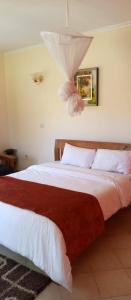 GituraEQUINE RESORT的一间卧室配有一张带白色和红色床单的大床