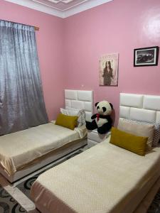 马拉喀什Riad malak的一间卧室配有两张床和一只塞满食物的熊猫熊