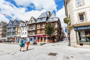 拉尼翁Grand studio lumineux proche gare Lannion et plage的两个人沿着城市街道走,街道上建有建筑