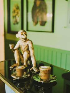 圣地亚哥Hotel Eco Boutique Bidasoa的坐在桌子上的猴子雕像,带两个咖啡杯