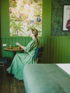 圣地亚哥Hotel Eco Boutique Bidasoa的坐在绿色房间里桌子上的女人
