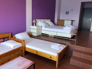 卢特拉艾季普苏Maravellia的紫色墙壁的客房内的三张床