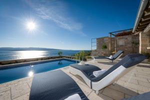 穆尔维察Luxury Villa Murvica with private pool near the beach in Murvica on Brac island的一座房子旁的游泳池,配有两把躺椅