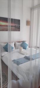 蒙巴萨La Mera Beachfront Apartment的一间卧室配有带白色床单和蓝色枕头的床。