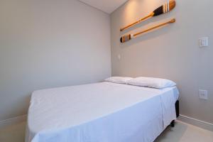 南圣弗朗西斯科Pousada Kauai SFS的一间小卧室,配有一张白色的床和壁挂式棒球棒