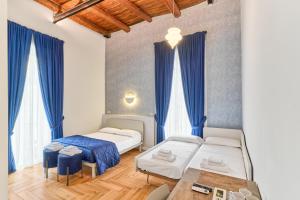 那不勒斯Toto e Peppino luxury rooms的配有蓝色窗帘的客房内的两张床