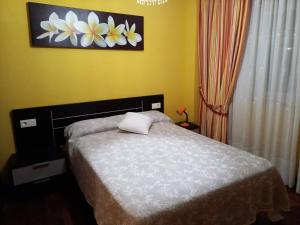 塞代拉Vacaciones的卧室配有一张床,墙上挂有花卉画