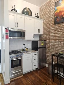 纽约The Harlem Getaway的厨房配有白色橱柜和不锈钢用具