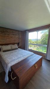 南卡希亚斯Casa aconchegante em meio a natureza的一间卧室设有一张大床和一个大窗户