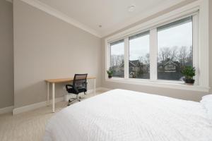 温哥华Luxurious 6-Bedroom Mansion Near UBC的白色的卧室设有书桌、床和窗户