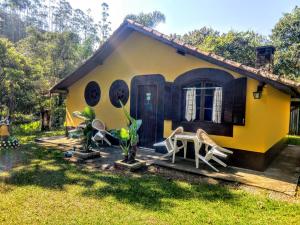 圣弗朗西斯科泽维尔Cachoeira do Roncador的黄色的房子前面设有桌椅