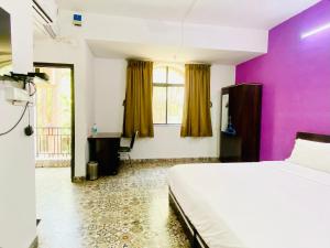 浦那Budget Private Ac Room with Kitchen Near Osho Garden的一间卧室配有一张床和紫色的墙壁